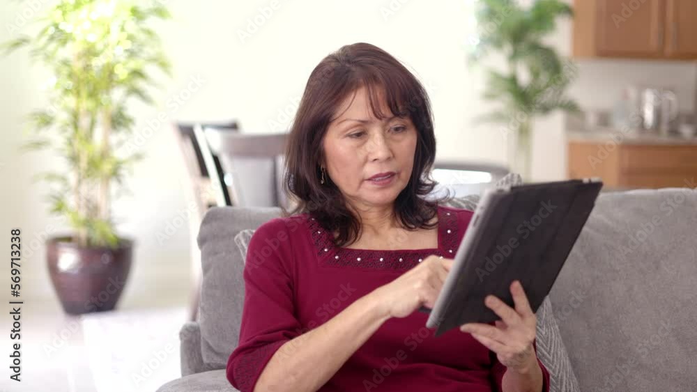 Beautiful middle age woman relaxing shopping online on mobile tablet, e-commerce credit card excited with purchase sitting on comfortable couch in leisure home living room Beautiful middle age woman relaxing shopping online on mobile tablet, e-commerce credit card excited with purchase sitting on comfortable couch in leisure home living room