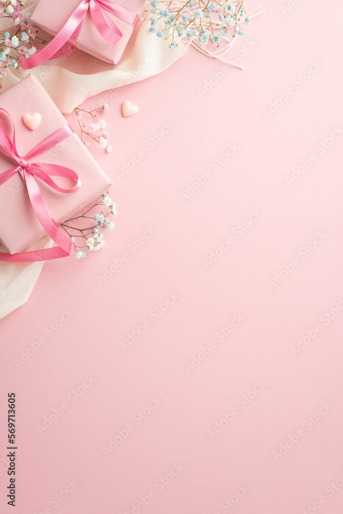 Spring gifts concept. Top view vertical photo of pink gift boxes with ribbon bows white soft scarf small hearts and gypsophila flowers on isolated pastel pink background with copyspace