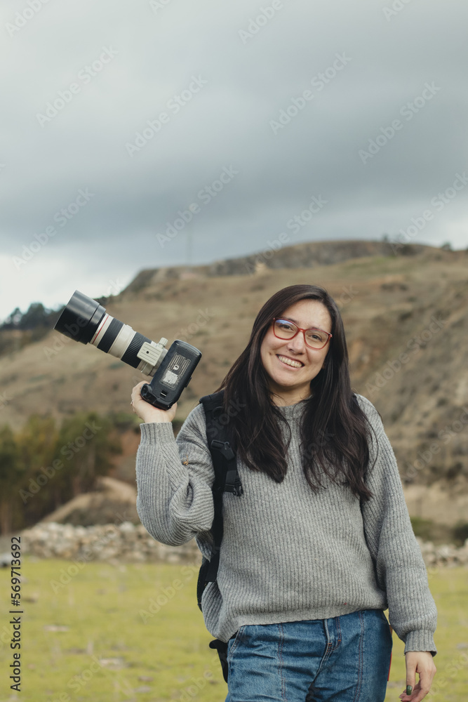 Portrait of a woman photographer smiling with her camera in her hand in a part of the Andes mountain range in Peru. Concept professions, people, travels and vacations.
