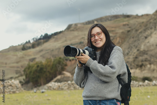 Portrait of a woman photographer smiling with her camera in her hand in a part of the Andes mountain range in Peru. Concept professions, people, travels and vacations. photo