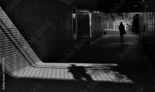 street harrasment and me too movement concept, shadow of a man and young girl in a railway station, unrecognizable persons, black and white photo