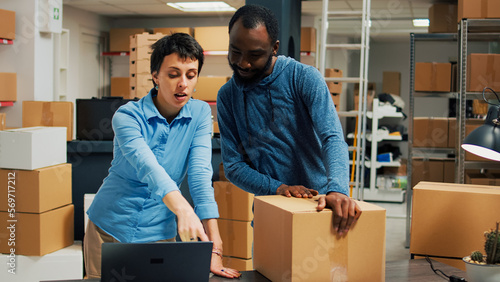 Happy entrepreneurs doing highfive sign in warehouse space, feeling pleased about finishing packing order with merchandise. Diverse team of workers preparing products in cardboard boxes.