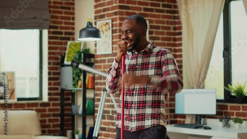 Wallpaper Mural Modern happy boyfriend having fun with music while he uses mop to wash floors, mopping in apartment. Young male adult dancing and singing in living room, spring cleaning enjoyment. Torontodigital.ca