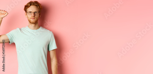 Confident redhead man standing united with black lives matter movemet, showing raised fist and looking serious at camera, protesting and being an activist, standing over pink background photo