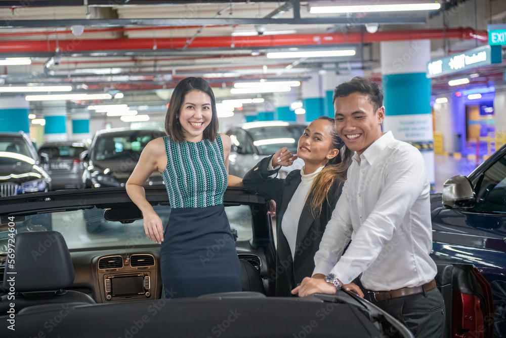 Happy asian young friends discover their new sports car. Two girls and a boy Happy asian young friends discover their new sports car. Two girls and a boy