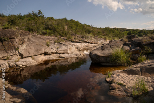View of the calm river flowing across the rocky hills and forest. The landscape reflection in the water surface. 