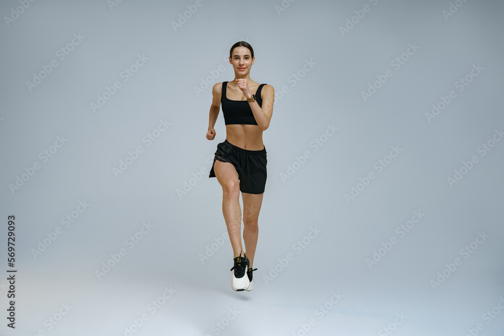 Athletic active woman wearing sportswear running on studio background. Dynamic movement