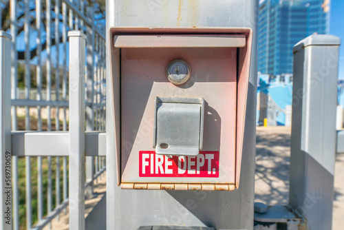 Fire alarm box on a post with Fire Dept. sticker sign below at Waterloo Park in Austin, Texas. Emergency fire box with lock on a gray post of railings. photo