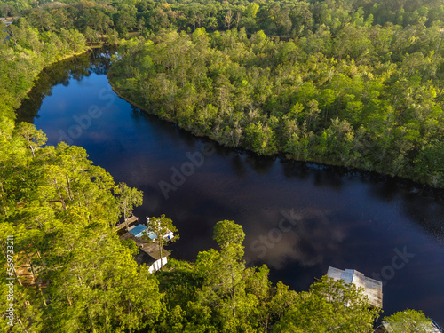 High angle view of a river in a forest with residences and green trees at Navarre  Florida. Reflective black river waterway with tall trees on the shore.