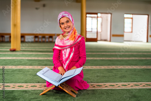 Canvas Print A happy Muslim girl reading a holy book Quran inside the mosque.