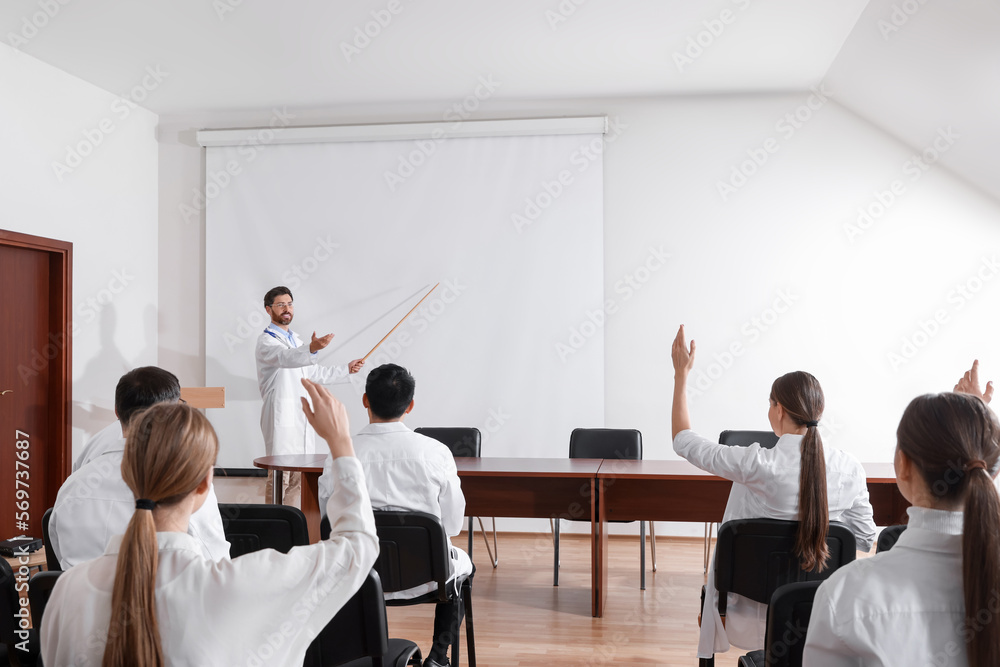 Doctor giving lecture in conference room with projection screen Doctor giving lecture in conference room with projection screen