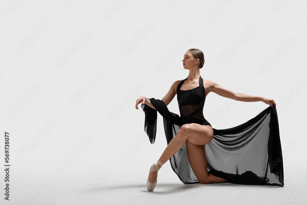 Graceful young ballerina practicing dance moves with black veil on white background. Space for text Graceful young ballerina practicing dance moves with black veil on white background. Space for text