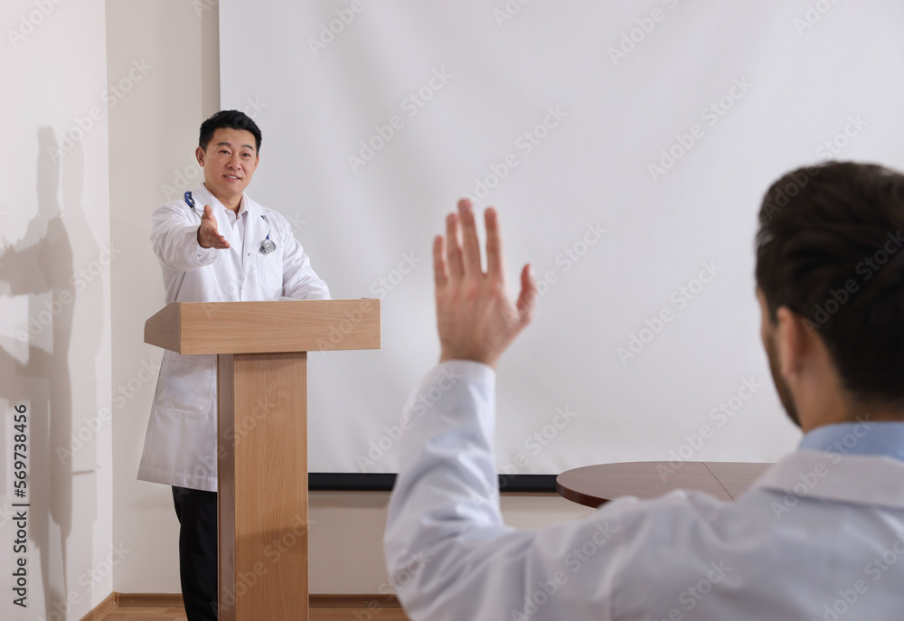Doctor giving lecture in conference room with projection screen Doctor giving lecture in conference room with projection screen
