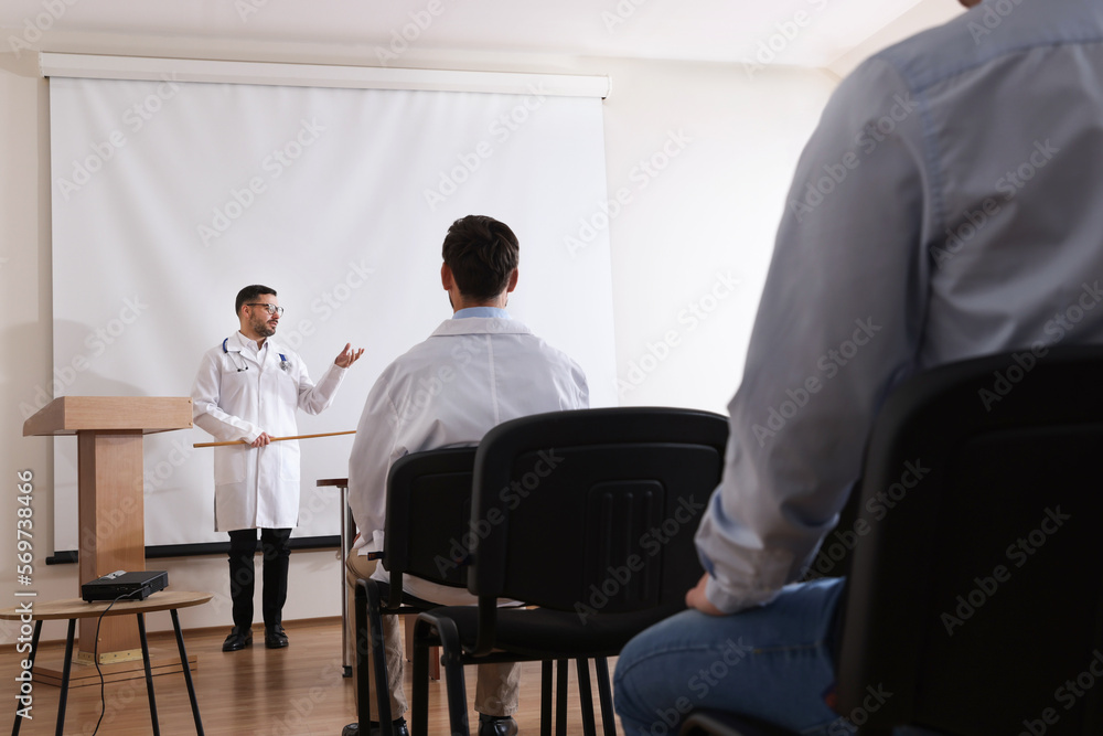 Doctor giving lecture in conference room with projection screen
