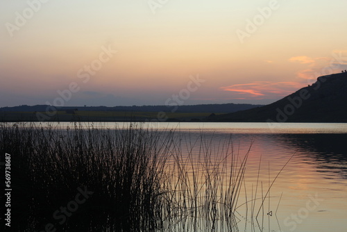 Fototapeta Naklejka Na Ścianę i Meble -  Atardecer en una hermosa laguna, junto a sierras y plantas
