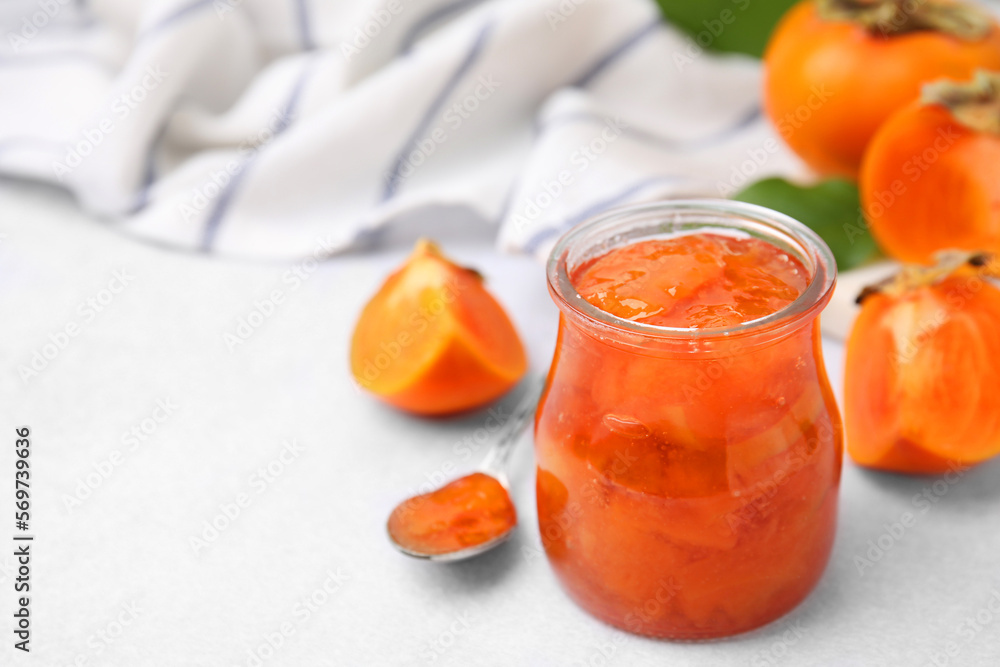 Jar of tasty persimmon jam and ingredients on white table. Space for text Jar of tasty persimmon jam and ingredients on white table. Space for text