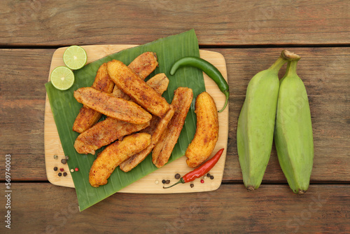 Delicious fried bananas, fresh fruits and different peppers on wooden table, flat lay