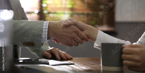 Business partners shaking hands at table after meeting in office, closeup. Banner design