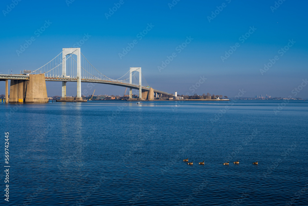 Fototapeta premium Bridge over the bay, birds swimming in the sea, sunrise light shining on