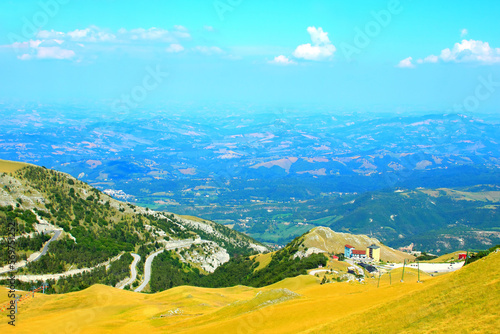 Particular view from Sassotetto at the mountainous landscapes of the Sibillini with sparse buildings and rich vegetation and an immense view over the neighbouring lands as far as the eye can see photo