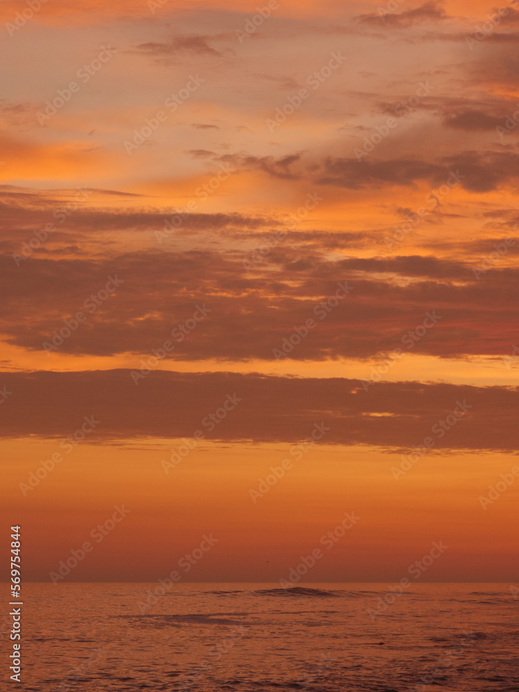 Sunset on the beach, golden hour, the sky is painted in orange and yellow colors