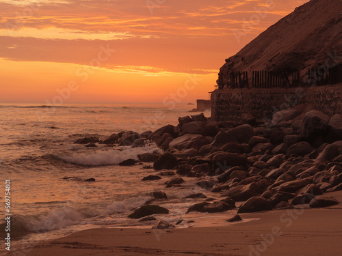 Sunset at El silencio beach, Lima, Peru. Golden hour, the ocean breaking on the rocky shore