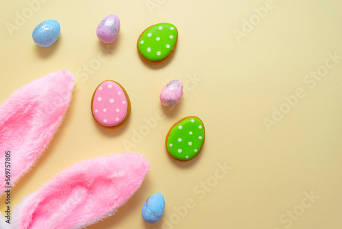 Happy easter. Pastel colors Easter eggs with cookies on beige background.