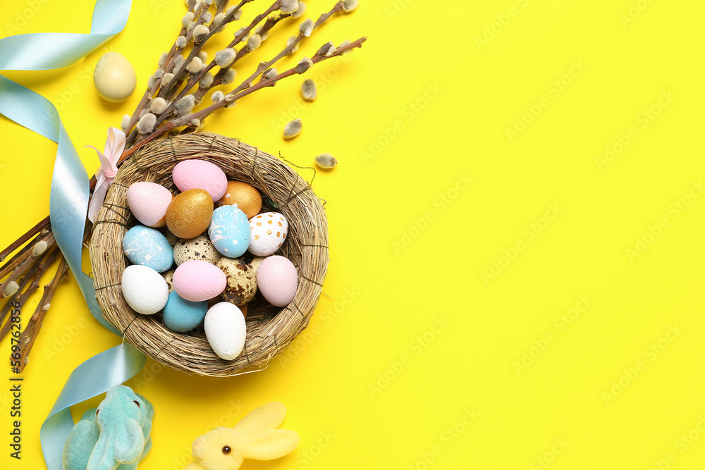 Composition with nest of Easter eggs, willow branches and toy bunnies on yellow background Stock