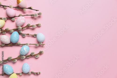Composition with willow branches and beautiful Easter eggs on pink background