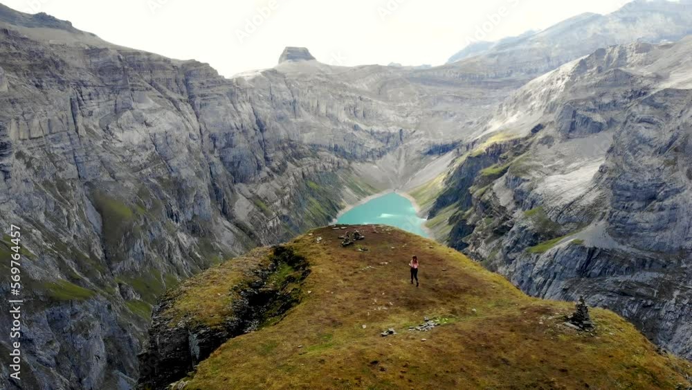 A hiker running towards the viewpoint of lake Limmernsee in Glarus, Switzerland, the turquoise colored water of which is surrounded by tall Swiss Alps peaks and cliffs A hiker running towards the viewpoint of lake Limmernsee in Glarus, Switzerland, the turquoise colored water of which is surrounded by tall Swiss Alps peaks and cliffs