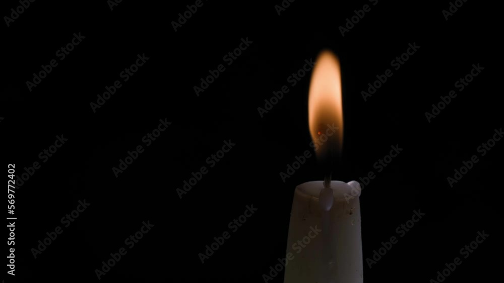 An ordinary white candle burns close-up on a black background. A paraffin candle burns in the right corner of the frame, close-up, space for text. Ceremony of mourning and remembrance of the dead An ordinary white candle burns close-up on a black background. A paraffin candle burns in the right corner of the frame, close-up, space for text. Ceremony of mourning and remembrance of the dead