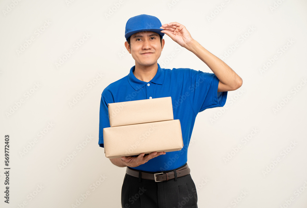 Happy delivery asian man in blue uniform standing holding box parcel cardboard on isolated white background. Smiling male service worker. Delivery courier and shipping service. Happy delivery asian man in blue uniform standing holding box parcel cardboard on isolated white background. Smiling male service worker. Delivery courier and shipping service.
