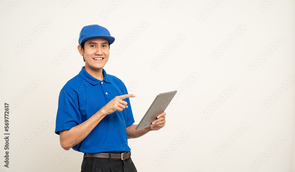 Asian man in blue uniform standing holding digital tablet computer on isolated white background. Male service worker with cell phone. Delivery courier shipping service Asian man in blue uniform standing holding digital tablet computer on isolated white background. Male service worker with cell phone. Delivery courier shipping service