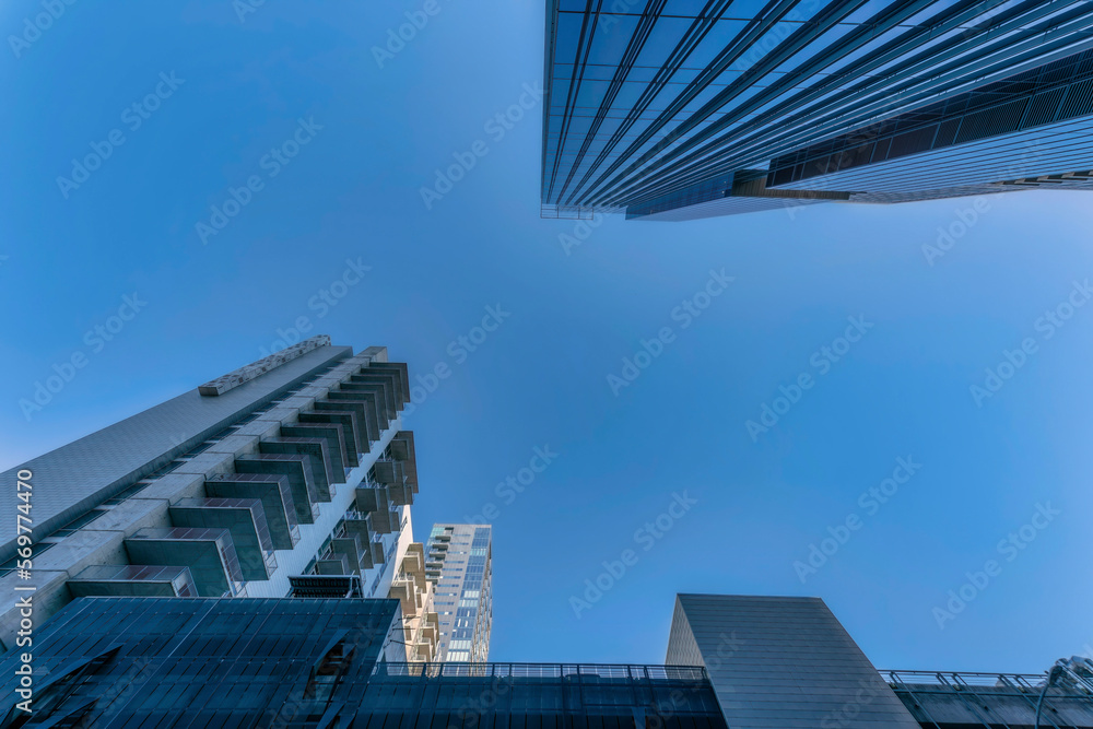 Looking up at exterior of apartments or condominium towering against blue sky. Austin Texas skyline with facade of modern buildings featuring glass windows and balconies.