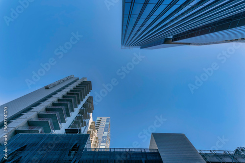 Looking up at exterior of apartments or condominium towering against blue sky. Austin Texas skyline with facade of modern buildings featuring glass windows and balconies.