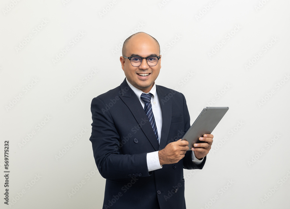 Portrait of Young asian businessman using digital tablet on isolated white background. Handsome middle aged Indian businessman holding tablet computer in office uniform. Portrait of Young asian businessman using digital tablet on isolated white background. Handsome middle aged Indian businessman holding tablet computer in office uniform.
