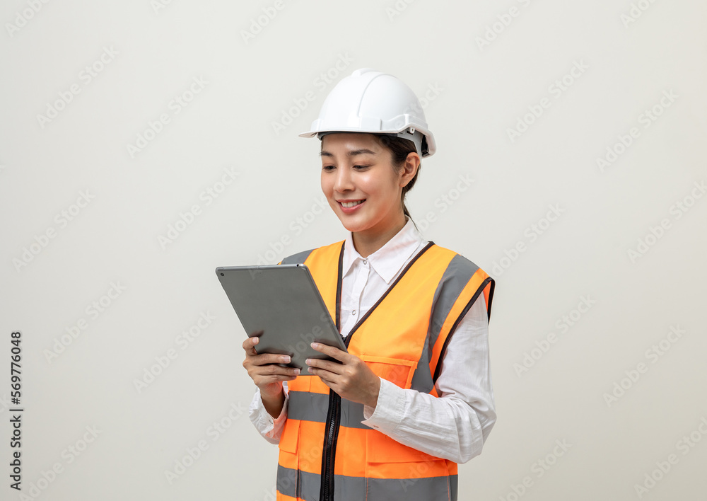 Asian engineer worker woman or architect with white safety helmet standing on isolated white background. Mechanic service factory Professional job occupation in uniform working with tablet Asian engineer worker woman or architect with white safety helmet standing on isolated white background. Mechanic service factory Professional job occupation in uniform working with tablet
