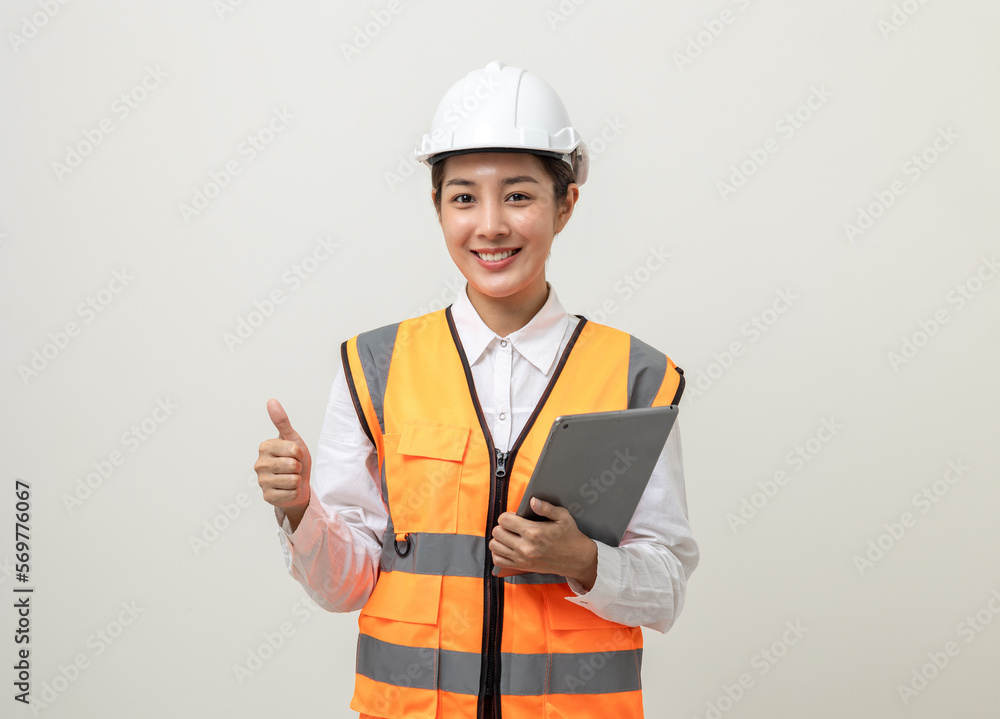 Asian engineer worker woman or architect with white safety helmet standing on isolated white background. Mechanic service factory Professional job occupation in uniform working with tablet Asian engineer worker woman or architect with white safety helmet standing on isolated white background. Mechanic service factory Professional job occupation in uniform working with tablet