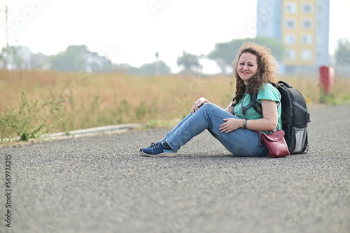 woman sitting on the road. hiking deep into the wilderness, or going on tours with local experts. Woman traveler goes beyond city skylines and sweeping landscapes. long trip road