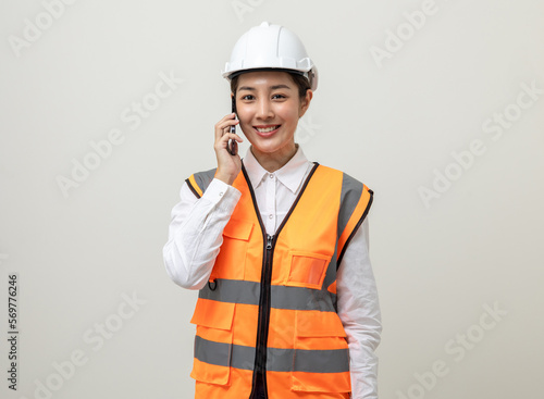 Asian engineer worker woman or architect with white safety helmet standing on isolated white background. Mechanic service factory Professional job occupation in uniform working with smartphone