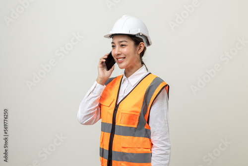 Asian engineer worker woman or architect with white safety helmet standing on isolated white background. Mechanic service factory Professional job occupation in uniform working with smartphone