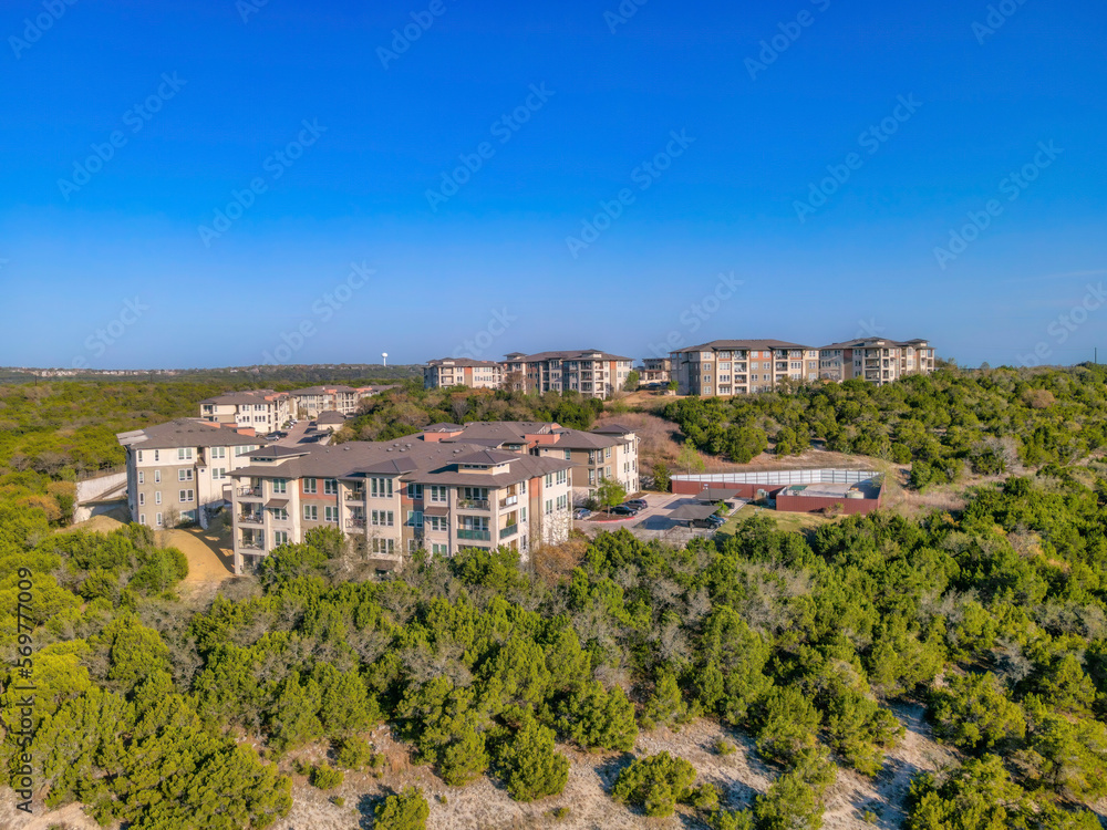 Austin, Texas- High angle view of complex apartments in the middle of forest. Multi-storey apartment buildings on top of a mountain slope and view of a clear blue sky background.