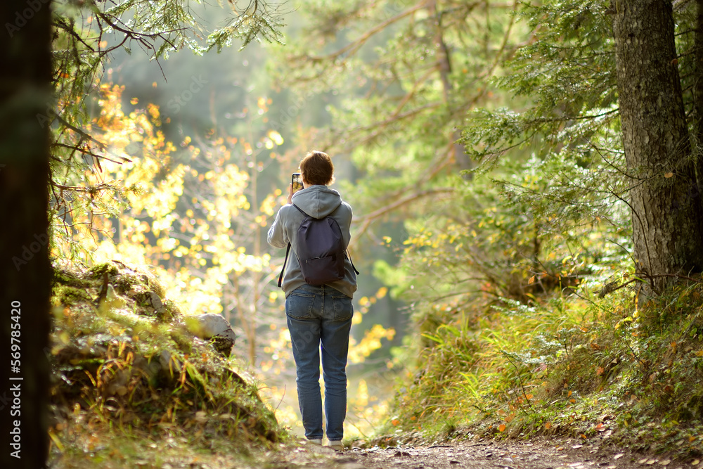 Woman tourist taking photo of scenic view of the forest in National Park Durmitor on autumn day. Hiking and travel. Woman tourist taking photo of scenic view of the forest in National Park Durmitor on autumn day. Hiking and travel.