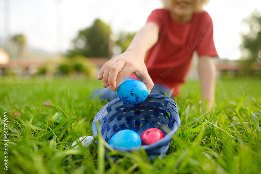 Little boy hunting for eggs in spring garden on Easter day. Traditional festival outdoors. Child celebrate Easter holiday. Focus on hand. Little boy hunting for eggs in spring garden on Easter day. Traditional festival outdoors. Child celebrate Easter holiday. Focus on hand.