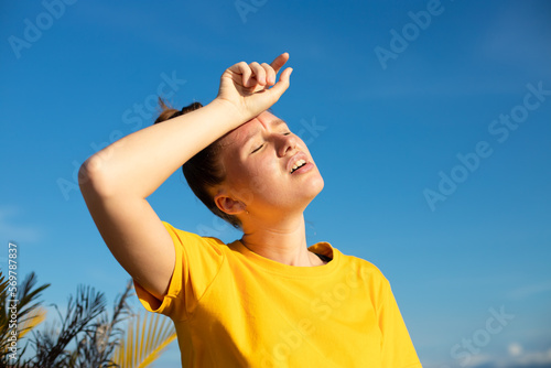 Girl is suffering from heat, woman with heatstroke. Having sunstroke at summer hot weather. Dangerous sun, girl under sunshine. Headache. Person holds hand on head. Feeling bad, unwell, unhealthy