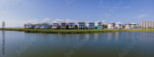Facade of houses with balconies overlooking the lagoon in Destin Florida. Panorama of a residential landscape surrounded by water against blue sky background.