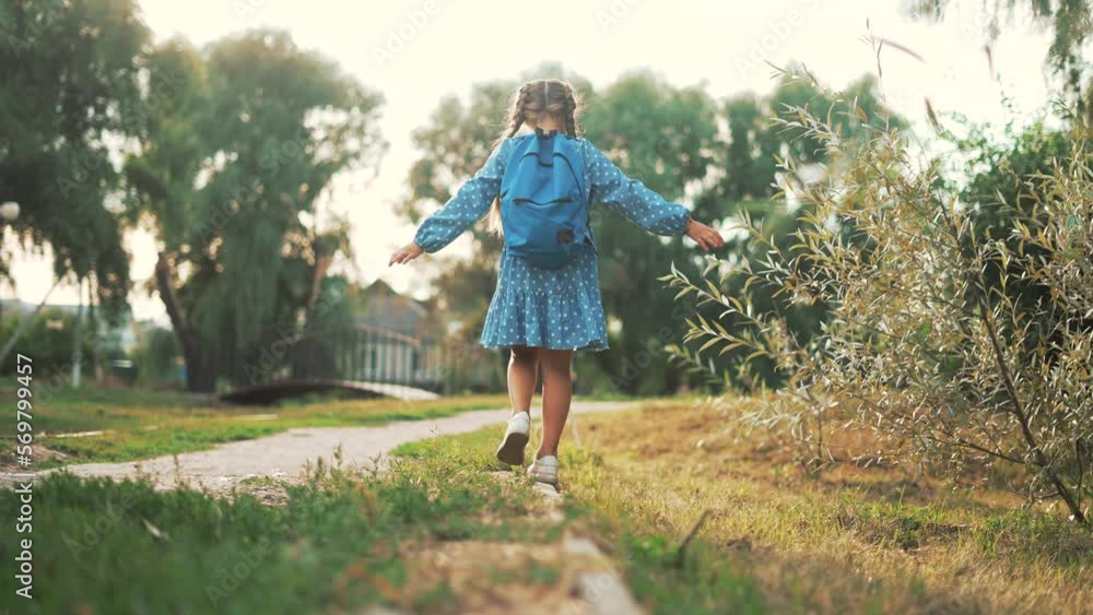 Happy girl with backpack goes to school. Child goes back to school. Girl walks along path in the park. Schoolboy with backpack goes to school. Children's education concept. Child goes to first grade Happy girl with backpack goes to school. Child goes back to school. Girl walks along path in the park. Schoolboy with backpack goes to school. Children's education concept. Child goes to first grade