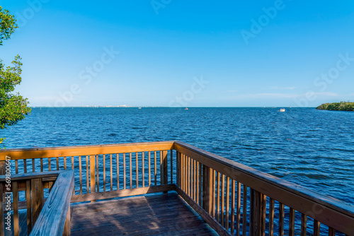 View from a corner of a boardwalk near the Dinner Key Marina at Miami, Florida. Wooden path with railings with a view of the blue ocean waters and clear sky background.