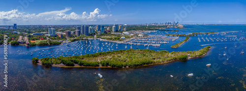 Aerial view of Dinner Key Marina and Coconut Grove Sailing Club in panorama at Miami, Florida. There is a small island at the front near the boats against the modern high rise buildings and sky . photo