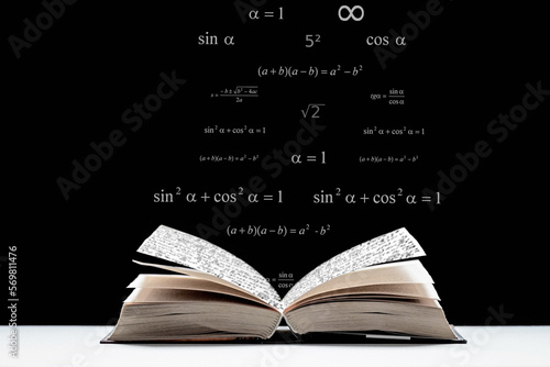 An open book, a textbook lies on the table. Metematic signs and formulas on a black background. The study of mathematics, algebra, geometry.